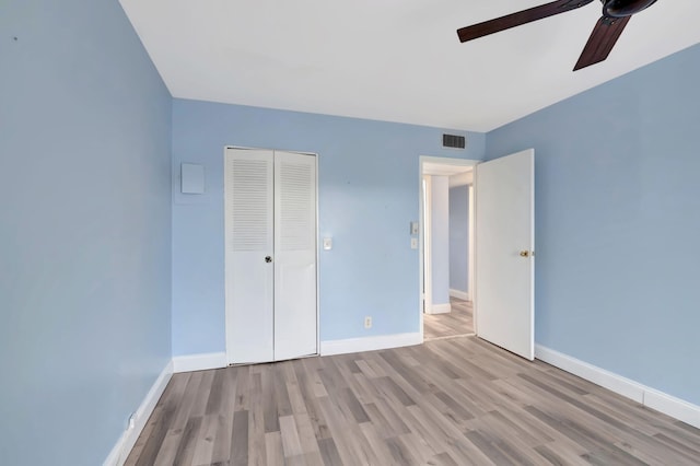 unfurnished bedroom with light hardwood / wood-style floors, ceiling fan, and a closet