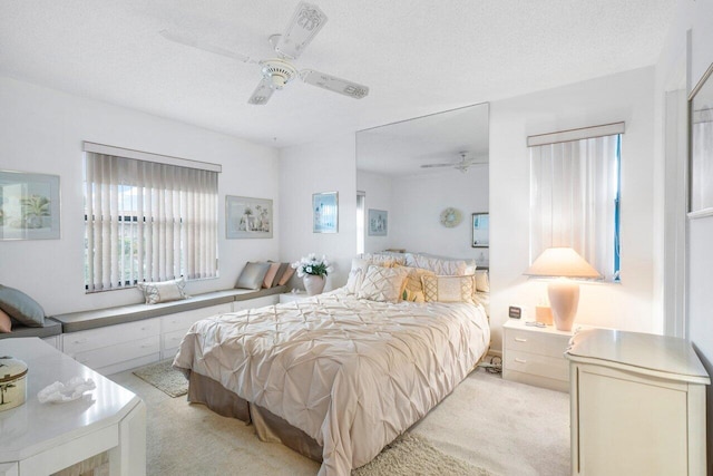 bedroom featuring a textured ceiling, ceiling fan, and light colored carpet