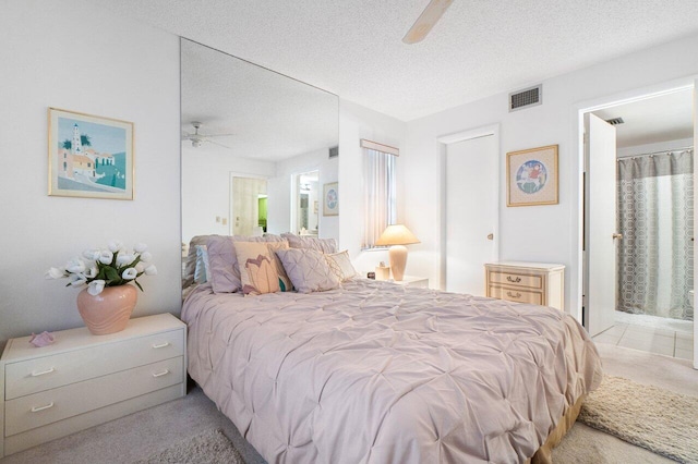 carpeted bedroom with a textured ceiling, ceiling fan, and connected bathroom