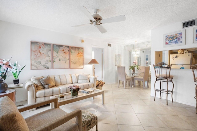 tiled living room with ceiling fan and a textured ceiling