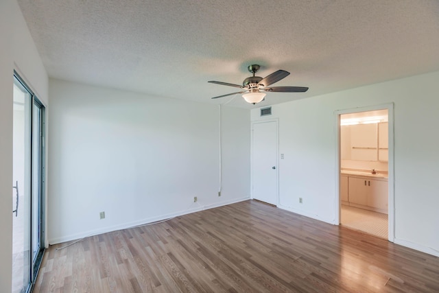 unfurnished bedroom with connected bathroom, a textured ceiling, ceiling fan, and light wood-type flooring