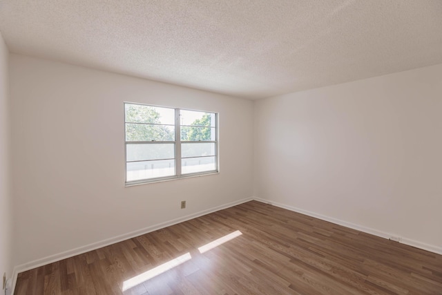 spare room with dark hardwood / wood-style flooring and a textured ceiling