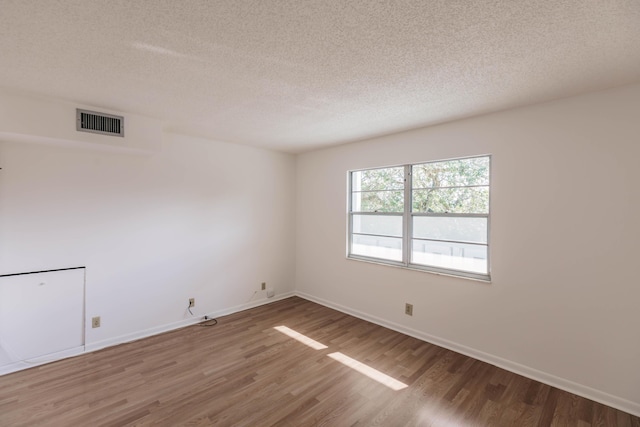 unfurnished room with a textured ceiling and hardwood / wood-style floors