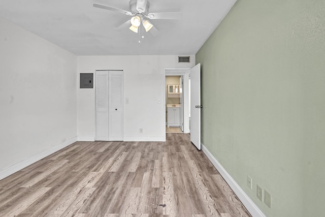 unfurnished bedroom with light hardwood / wood-style flooring, electric panel, ceiling fan, and a closet