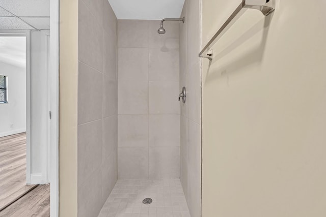 bathroom with tiled shower and wood-type flooring