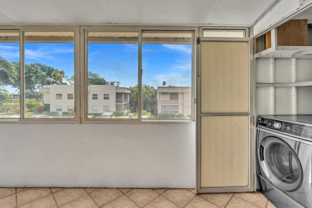 clothes washing area with washer / dryer, a wealth of natural light, and light tile patterned floors