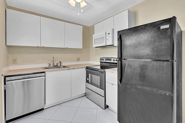 kitchen with light tile patterned floors, stainless steel appliances, white cabinetry, sink, and ceiling fan