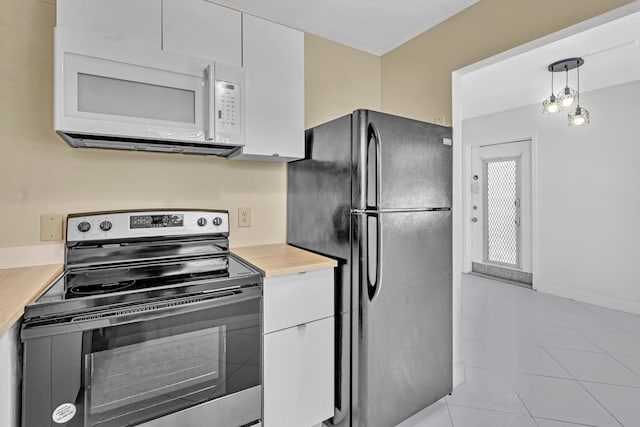 kitchen with white cabinetry, black refrigerator, light tile patterned floors, stainless steel electric stove, and hanging light fixtures