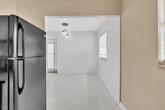 kitchen featuring hanging light fixtures, light tile patterned flooring, and black fridge