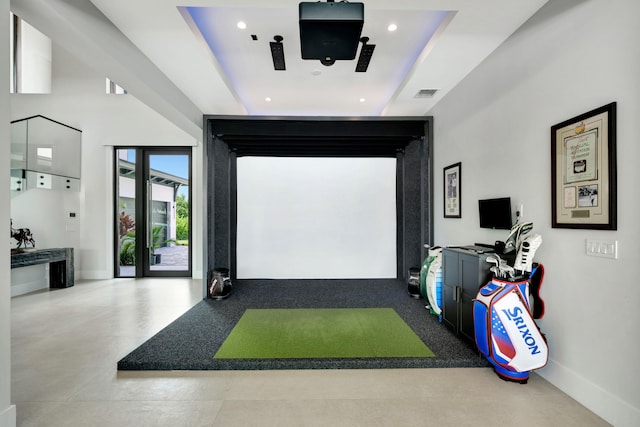 recreation room with a raised ceiling and golf simulator