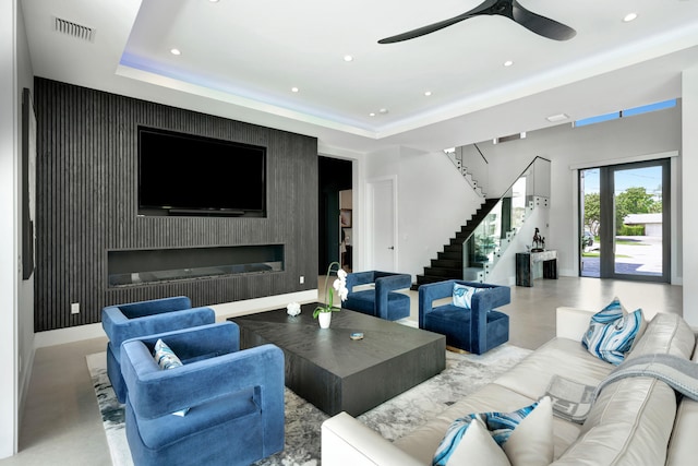 living room with a raised ceiling and ceiling fan