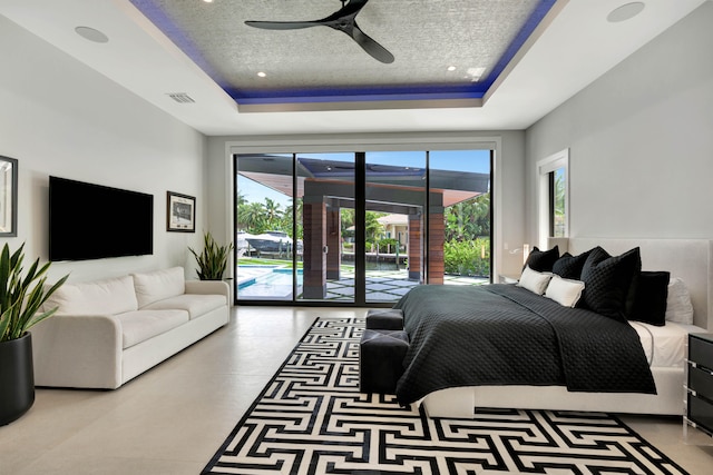 bedroom featuring a raised ceiling, a textured ceiling, access to exterior, and ceiling fan