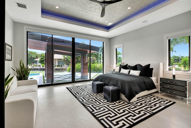 bedroom featuring multiple windows, access to outside, and a raised ceiling