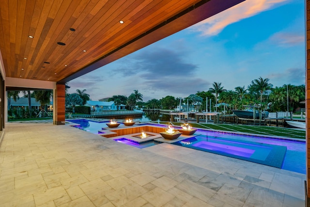 pool at dusk featuring an in ground hot tub and a patio area