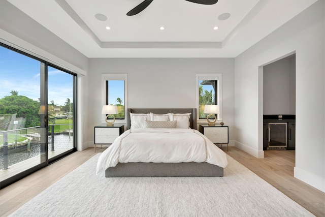 bedroom featuring access to exterior, ceiling fan, light wood-type flooring, and multiple windows