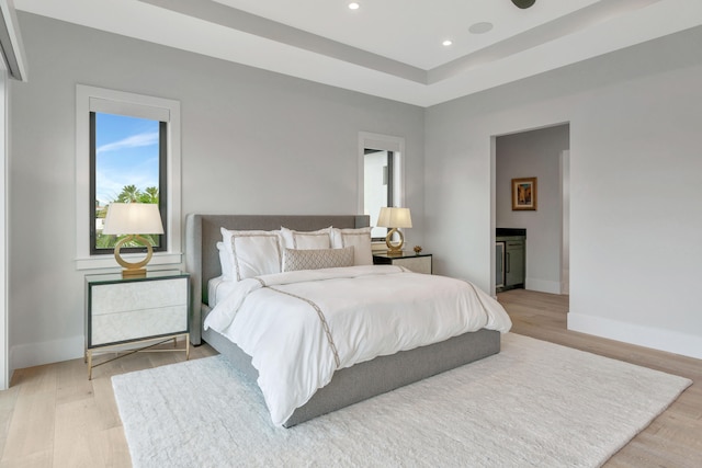 bedroom with connected bathroom and light wood-type flooring