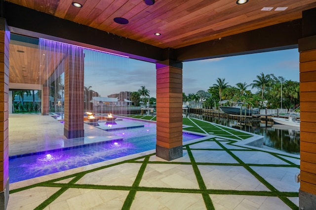 patio terrace at dusk with pool water feature and a water view