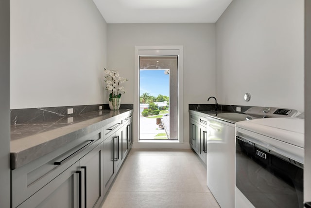 laundry area featuring independent washer and dryer, cabinets, and sink