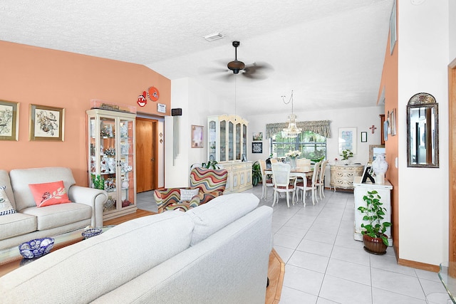 living room featuring ceiling fan with notable chandelier, vaulted ceiling, light tile patterned flooring, and a textured ceiling