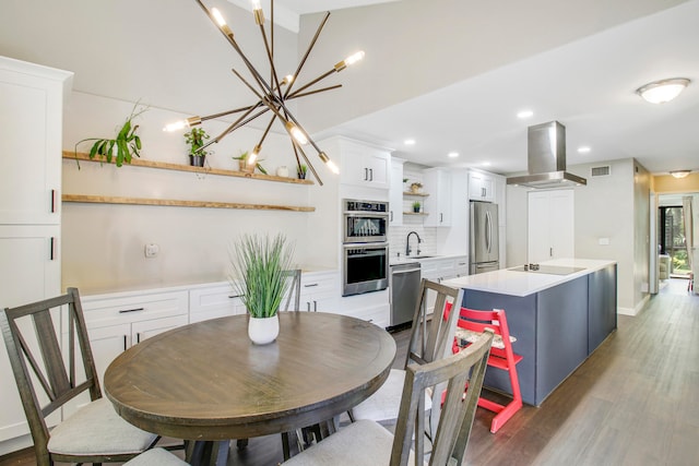 dining area featuring sink, light hardwood / wood-style flooring, and a chandelier