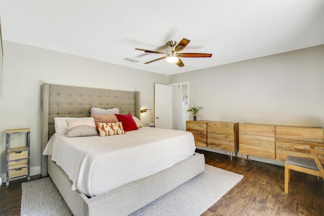 bedroom with a textured ceiling, dark wood-type flooring, visible vents, and a ceiling fan