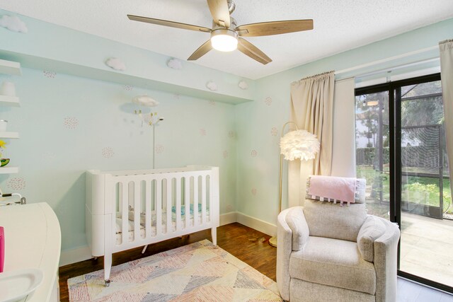 bedroom featuring ceiling fan, hardwood / wood-style floors, and a crib