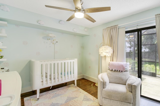 bedroom with a textured ceiling, multiple windows, baseboards, and wood finished floors