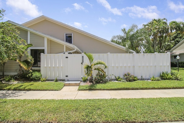 view of side of property with a lawn, fence, and a gate