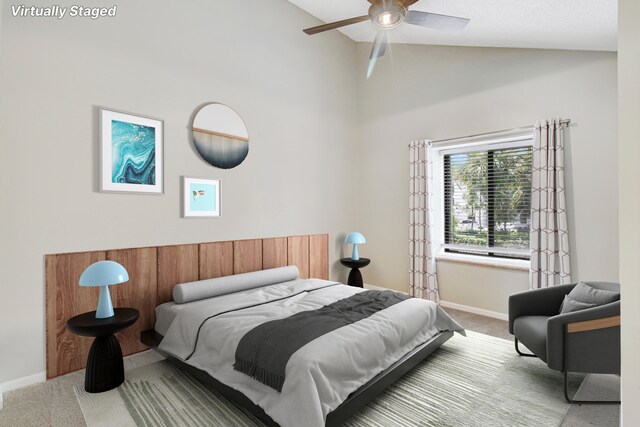 carpeted bedroom with ceiling fan and high vaulted ceiling