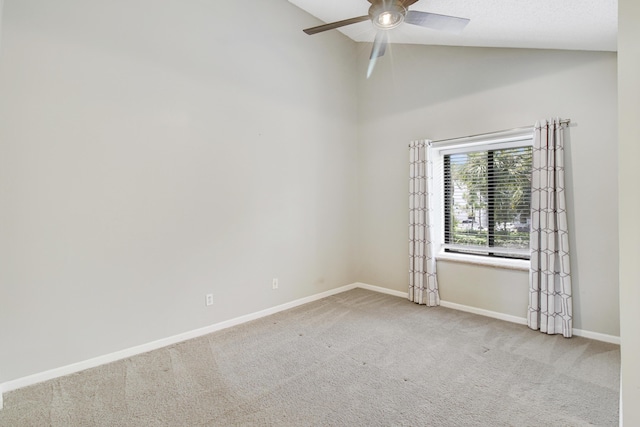 empty room with lofted ceiling, ceiling fan, baseboards, and light colored carpet