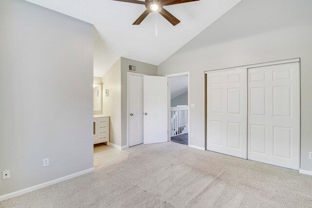 unfurnished bedroom featuring ensuite bath, high vaulted ceiling, ceiling fan, and light carpet