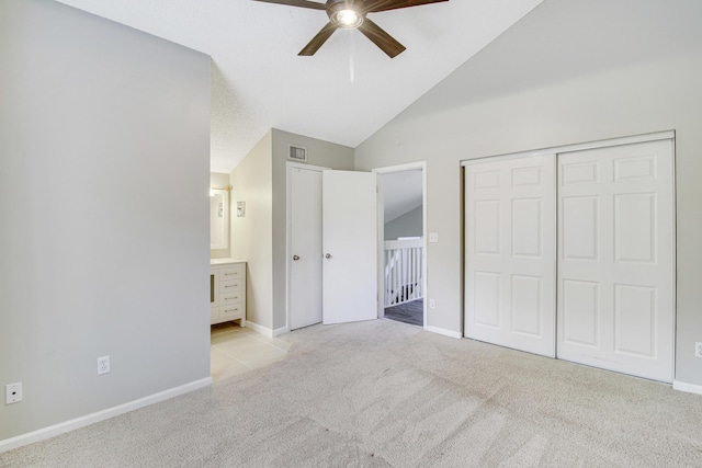 unfurnished bedroom with lofted ceiling, light colored carpet, visible vents, ensuite bathroom, and baseboards