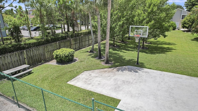 view of yard featuring fence and basketball hoop