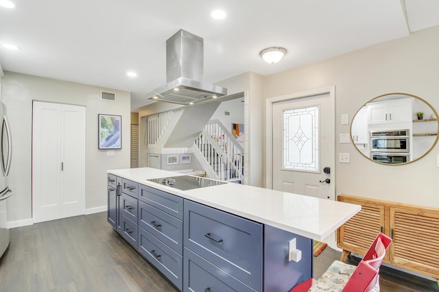 kitchen featuring black electric stovetop, island range hood, visible vents, light countertops, and a center island