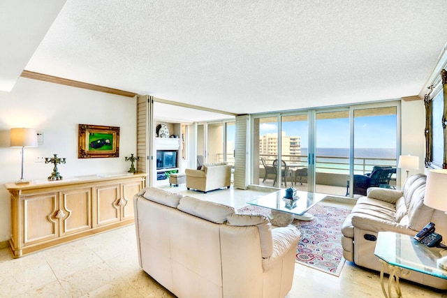 living room featuring a textured ceiling, a fireplace, floor to ceiling windows, and ornamental molding