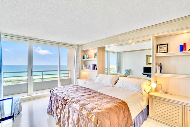 bedroom with a water view, multiple windows, access to exterior, and a textured ceiling