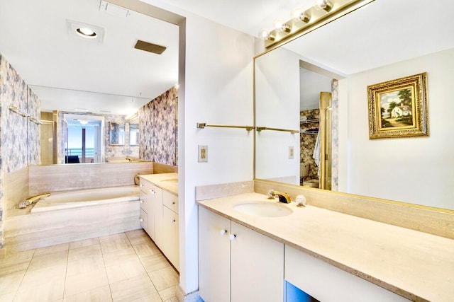 bathroom featuring tile patterned flooring, a bath, and vanity