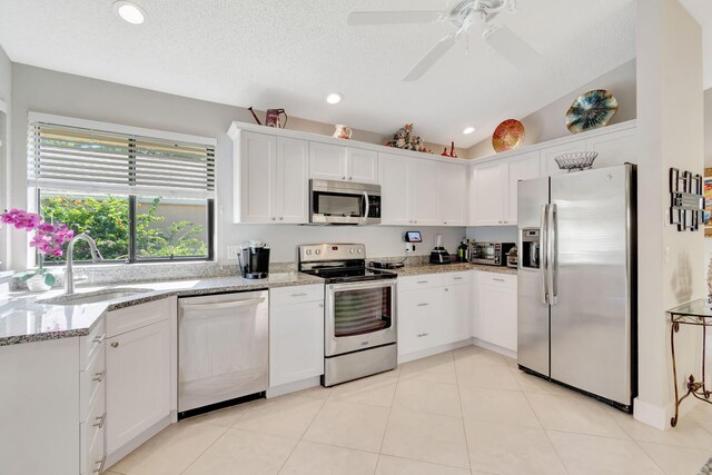 kitchen with light stone counters, sink, appliances with stainless steel finishes, and white cabinets