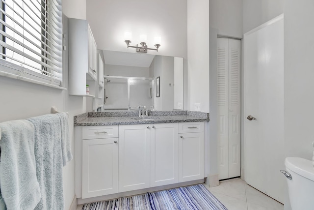 bathroom featuring vanity, toilet, tile patterned floors, and a shower with shower door