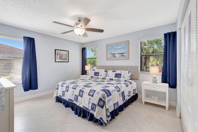 bedroom with a textured ceiling, light tile patterned floors, ceiling fan, and a closet