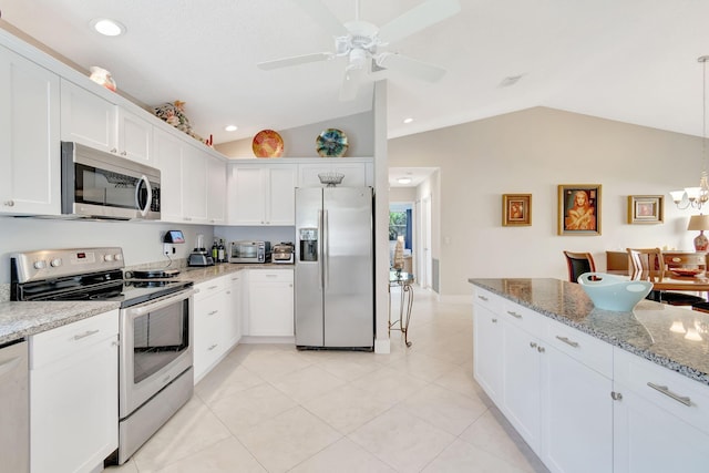 kitchen featuring ceiling fan with notable chandelier, vaulted ceiling, white cabinetry, and stainless steel appliances