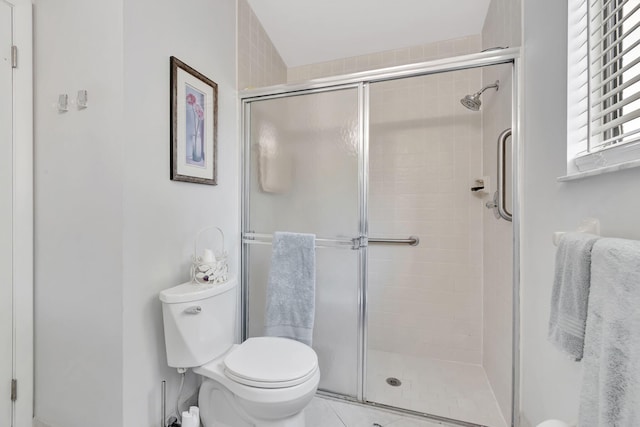 bathroom with a shower with door, toilet, and tile patterned floors