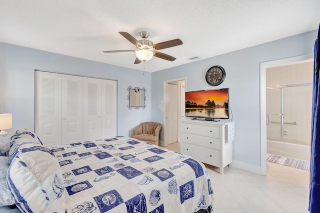 bedroom with light tile patterned floors, ensuite bathroom, a closet, ceiling fan, and a textured ceiling