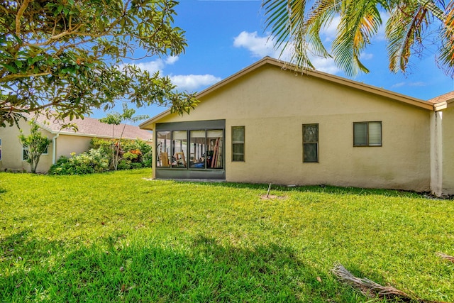 rear view of property with a lawn and a sunroom