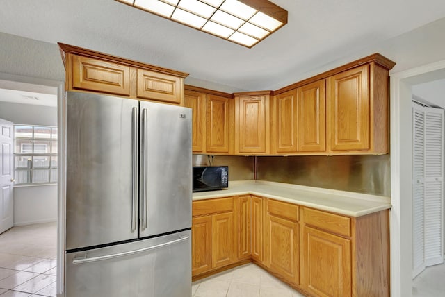 kitchen with light tile patterned flooring and stainless steel refrigerator