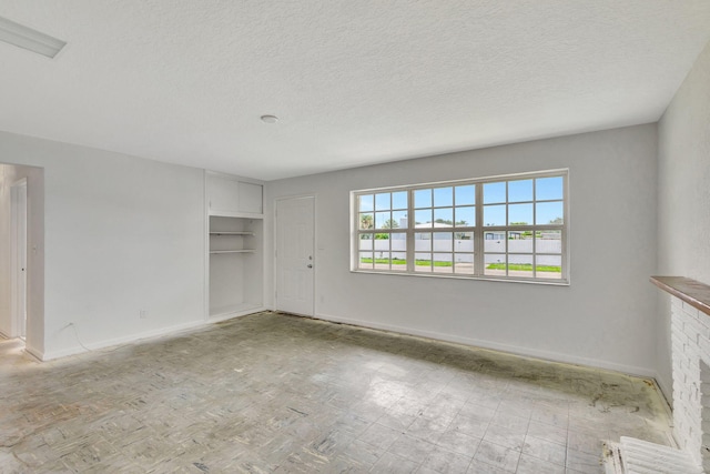 spare room featuring a textured ceiling and a fireplace