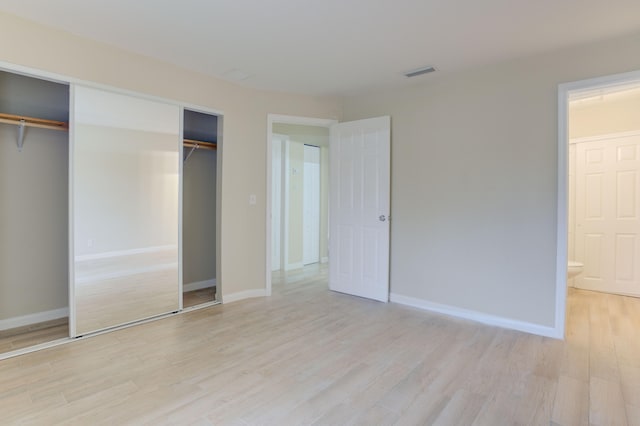 unfurnished bedroom with light wood-type flooring and ensuite bathroom