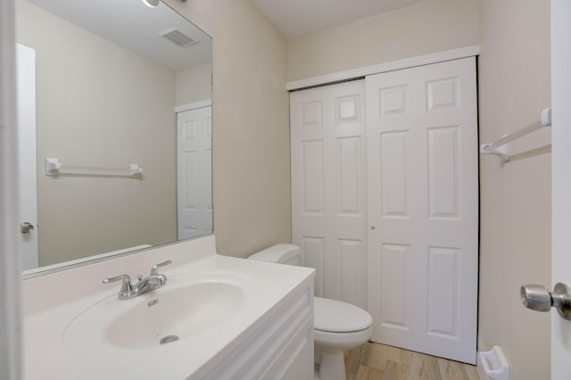 bathroom featuring toilet, vanity, and wood-type flooring