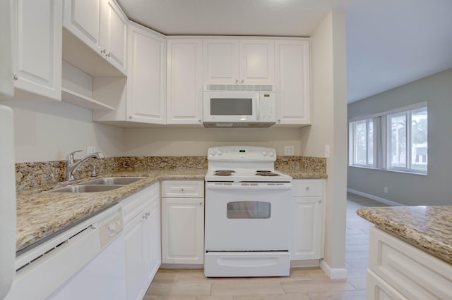 kitchen with sink, white appliances, white cabinetry, and light stone counters