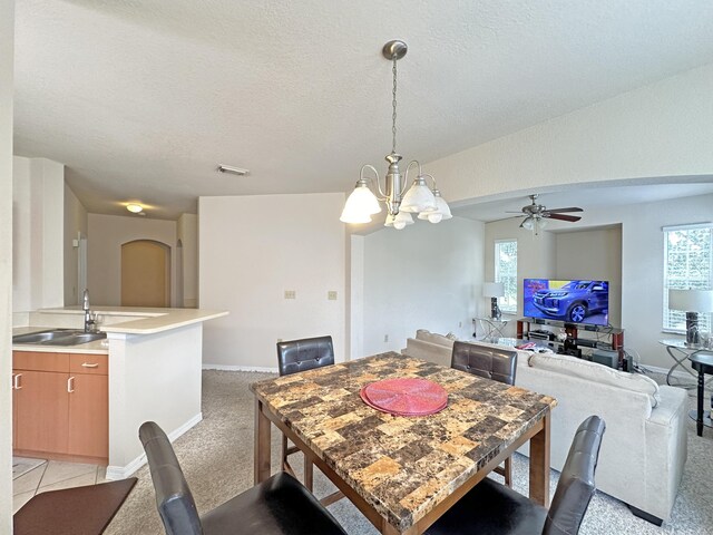 carpeted dining room featuring sink, a textured ceiling, and ceiling fan with notable chandelier